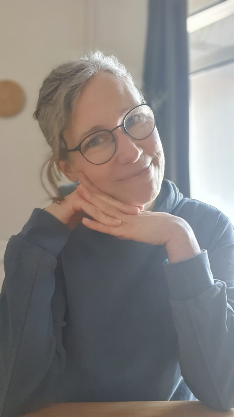 Katja am Tisch, den Kopf in die Hände gestützt